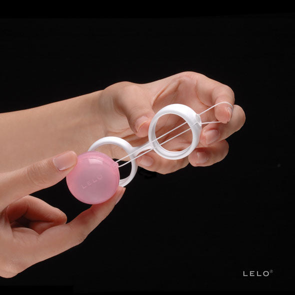 Main clipsant une boule rose Luna Beads Mini dans le support blanc de Lelo